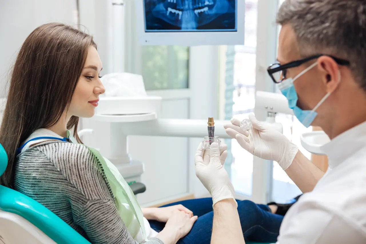 Dentist showing a dental implant to a patient during a consultation
