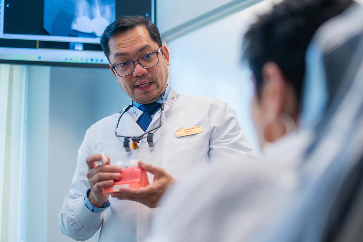 Dr. Oliver Austria showing a patient how dental implants work