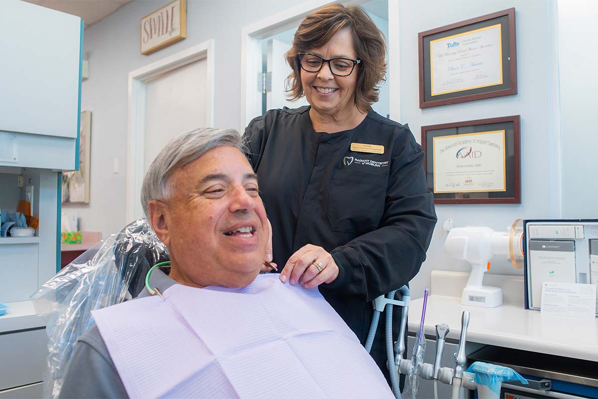 Dental hygienist attaching bib to preventive dentistry patient in preparation for a cleaning